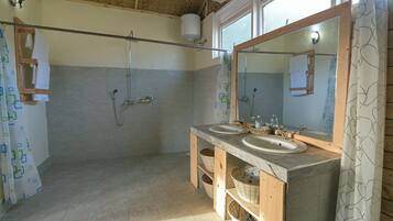 Un baño con dos lavamanos, ducha y espejo.