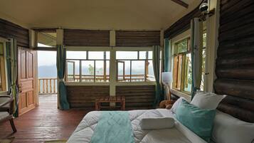 Habitació acollidora d'una cabana de fusta amb un llit, una banca de fusta i vistes a les muntanyes a través de grans finestres.