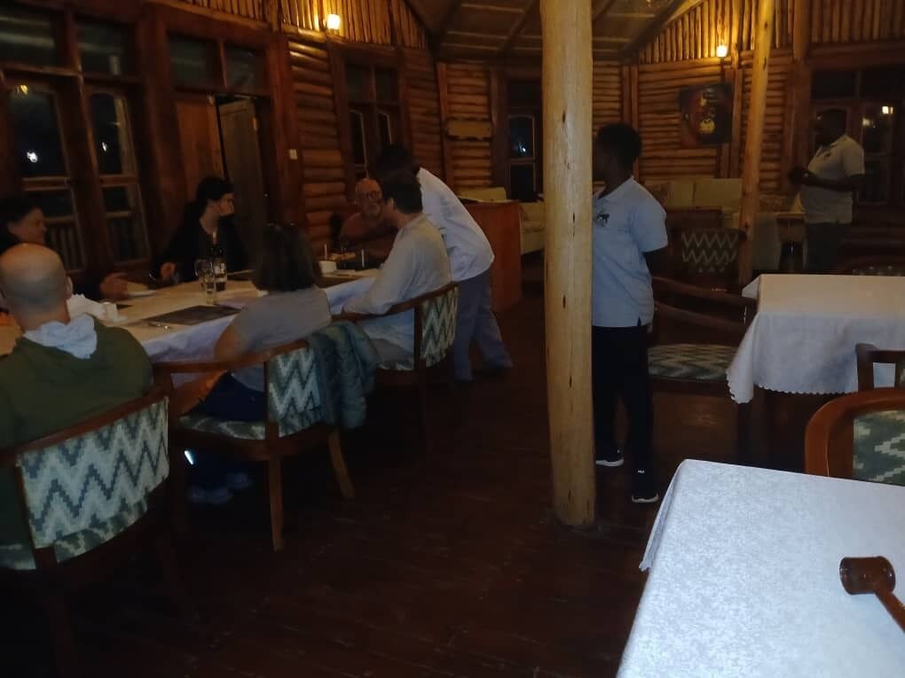 Un intérieur en bois avec des tables et des chaises, une personne debout et une autre qui marche.