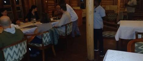 Un intérieur en bois avec des tables et des chaises, une personne debout et une autre qui marche.