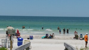 A beach with people swimming and sunbathing, a lifeguard stand, and beach chairs. - Gulf Coast Get-Away! Heated pool, sleeps 10! 69th (Largo)