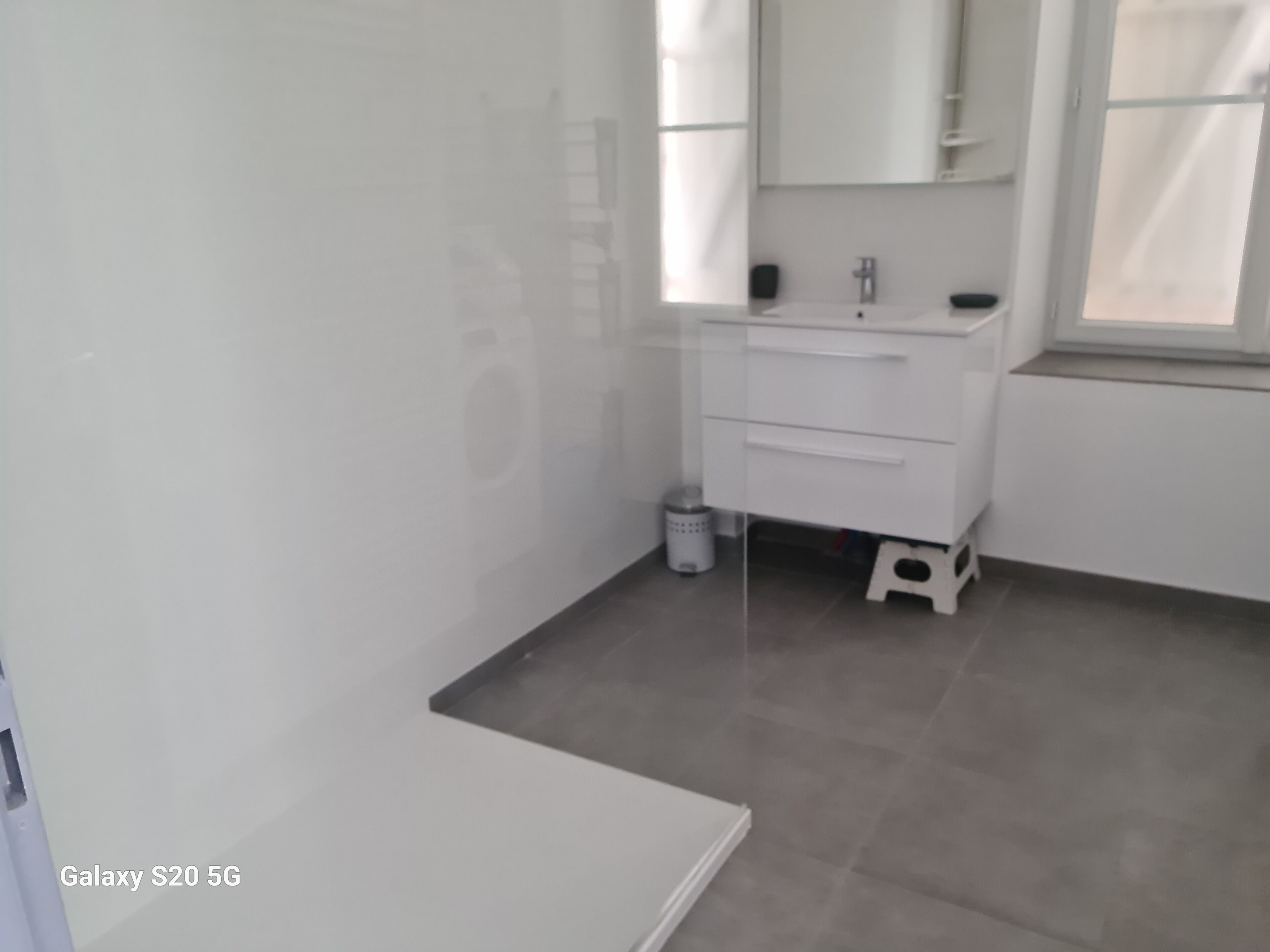 Un baño moderno con tocador blanco, un espejo y una ventana.