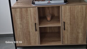 Ein Holzkabinent mit einer Ablage obenauf, einem Messerblock und einem kleinen Blumentopf.