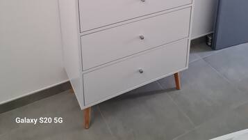 Un mobile bianco con un televisore a schermo piatto sopra, un telecomando e tre cassetti.