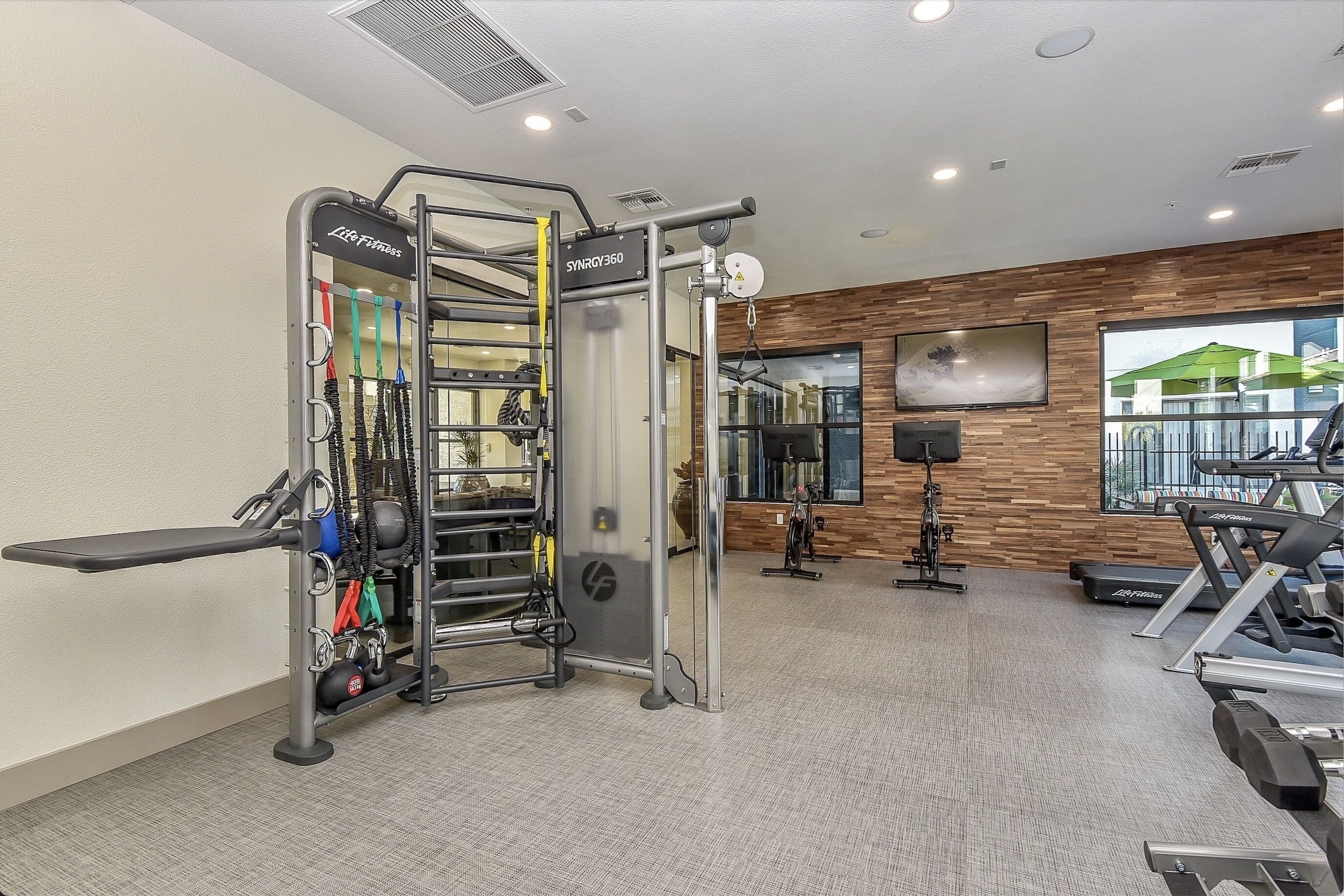 Un gimnasio con barra de dominadas, máquinas de pesas y cintas de correr.