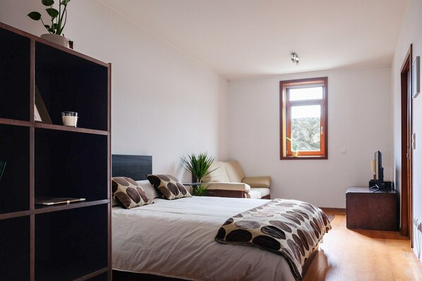 A bedroom with a bed, a bedside table, a chair, a window, and a wardrobe. - NEW! Boavista Studio 99 w/ Garage (Porto)