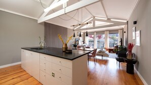 A modern kitchen with a central island, wooden flooring, and a dining area with a view.