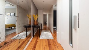 A modern hallway with wooden flooring, a glass partition, and a table with decorative items.
