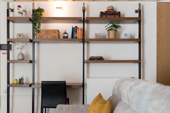 A living room with a sofa, a coffee table, and a bookshelf with decorative items and books.