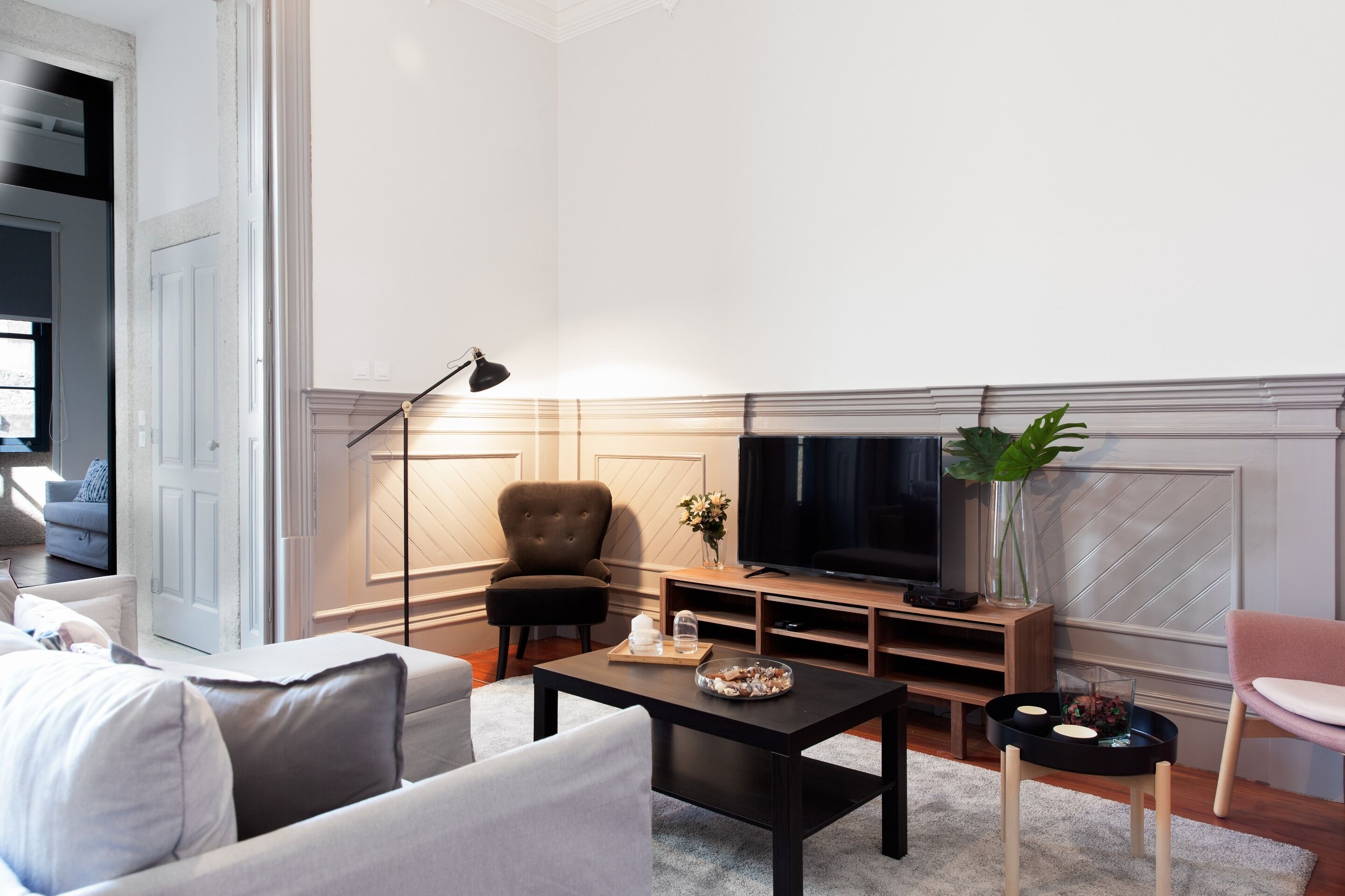 A modern living room with a sofa, armchair, coffee table, TV, and decorative items.