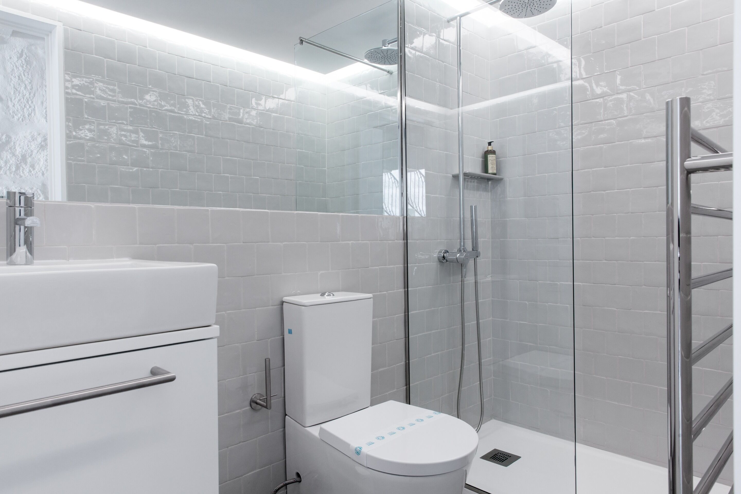 A modern bathroom with a glass shower enclosure, a white toilet, and a sink with a chrome faucet.