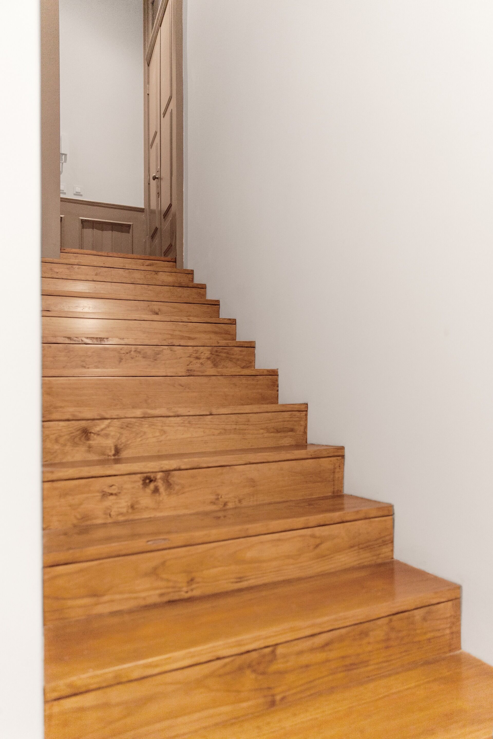 Eine Holztreppe mit Handlauf, die zu einer Tür führt.