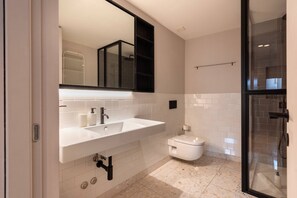 A modern bathroom with a white sink, mirror, and toilet.