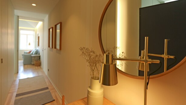 A hallway with a wooden floor, a mirror, a vase with dried flowers, and a lamp. - Prime Riverside near the river (Porto)