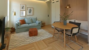 A modern living room with a light blue sofa, a wooden dining table, and a small orange ottoman. - Prime Riverside near the river (Porto)