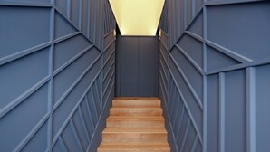 A wooden staircase with geometric wall panels and a light source at the top. - Prime Riverside near the river (Porto)