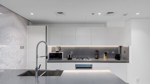A modern kitchen with a central island, stainless steel appliances, and recessed lighting. -  Maison Privee - Exquisite Duplex with Private Patio & Loft Living (Dubai)