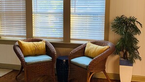 Ein Zimmer mit zwei Korbstühlen mit Kissen, einem kleinen Tisch und einer Topfpflanze.