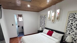 Une chambre avec un plafond en bois, un lit avec une literie blanche, un oreiller rouge et des panneaux décoratifs sur les murs.