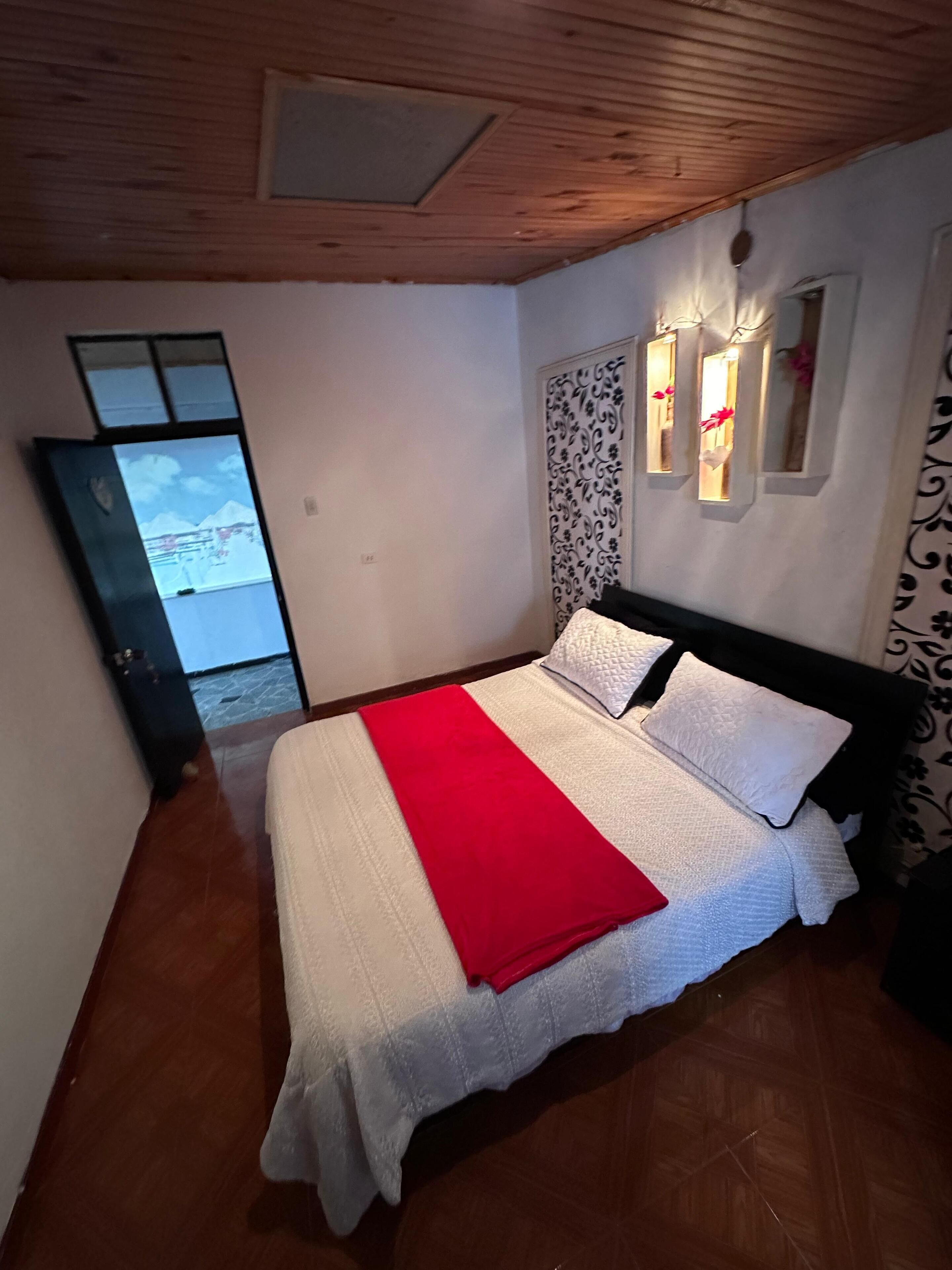 Un dormitorio con cama, techo de madera, ventana y pared con luces decorativas.