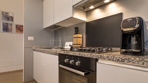 A modern kitchen with a built-in oven, a coffee maker, and a stainless steel range hood. - The Silk House - Travel Sustainable (Venezia)