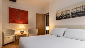 A hotel room with a large bed, two armchairs, a small table, and two lamps. - The Silk House - Travel Sustainable (Venezia)