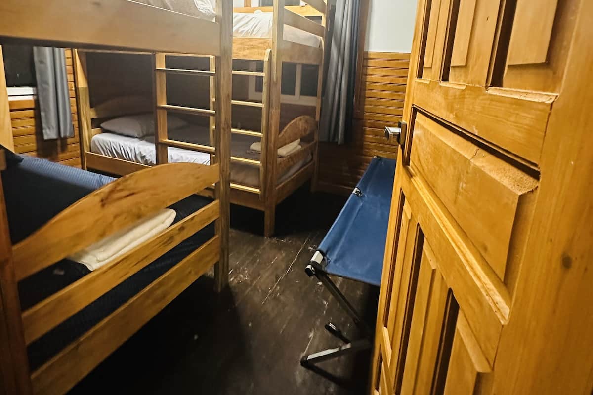 Habitación con literas, un armario de madera, una mesita y un aire acondicionado.