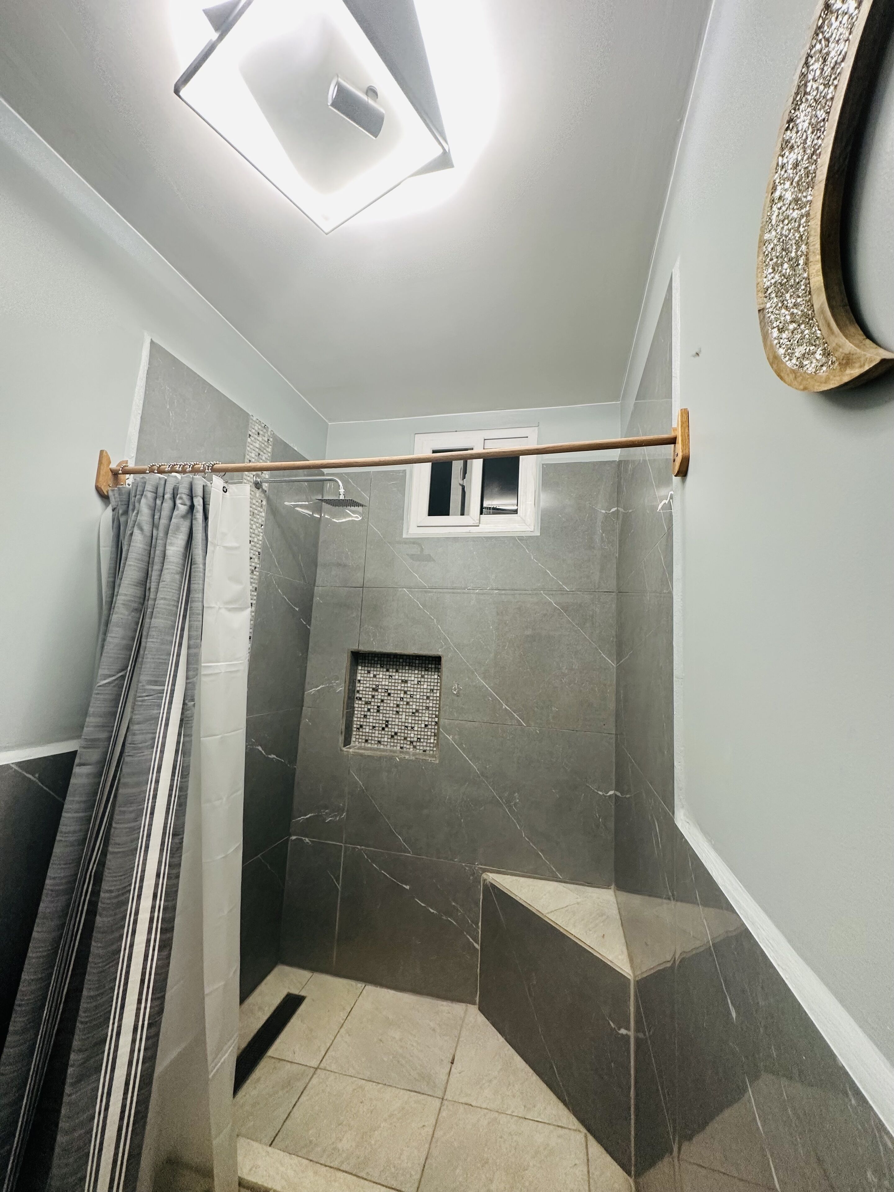 A modern bathroom with a shower, tiled walls, and a small window.