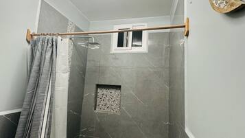 A modern bathroom with a shower, tiled walls, and a small window.