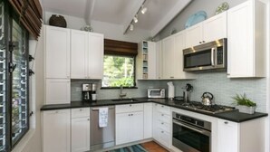 A modern kitchen with white cabinets, stainless steel appliances, and a black countertop.