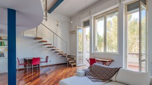 Un interior moderno con una escalera, un sofá y una zona de comedor.