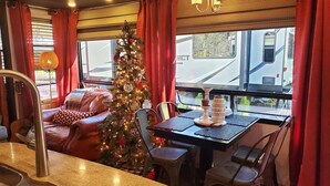 Ein Essbereich mit einem Weihnachtsbaum, roten Vorhängen und Blick auf einen Zug.