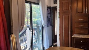 Eine Küche mit Spüle aus Edelstahl, Holzschränken und Blick ins Freie durch eine Glastür.