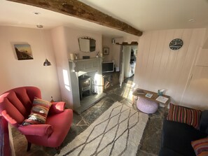 A cozy living room with a fireplace, a red armchair, a blue sofa, and a stone-patterned rug. - 400 year old Grade II listed stone cottage, Pilton; Glastonbury
AA 4* Gold Award (Pilton)