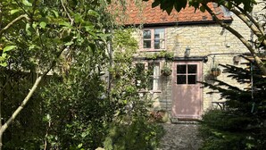 A stone building with a red-tiled roof, a wooden door, and a stone pathway leading to the entrance. - 400 year old Grade II listed stone cottage, Pilton; Glastonbury
AA 4* Gold Award (Pilton)
