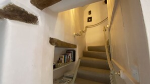 A staircase with a rope handrail, a shelf with books, and a small shelf with a book and a red object. - 400 year old Grade II listed stone cottage, Pilton; Glastonbury
AA 4* Gold Award (Pilton)