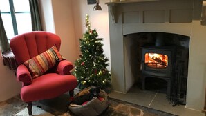 A cozy living room with a red armchair, a Christmas tree, and a fireplace. - 400 year old Grade II listed stone cottage, Pilton; Glastonbury
AA 4* Gold Award (Pilton)
