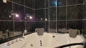 Et stilfuldt badeværelse med et stort fristående badekar, en bruseniche og et spejl.
