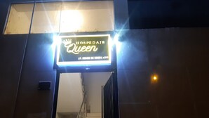 En neonskilte med teksten "HOSPDAJE Queen" og et krone-symbol, der angiver et hotel eller pensionat.