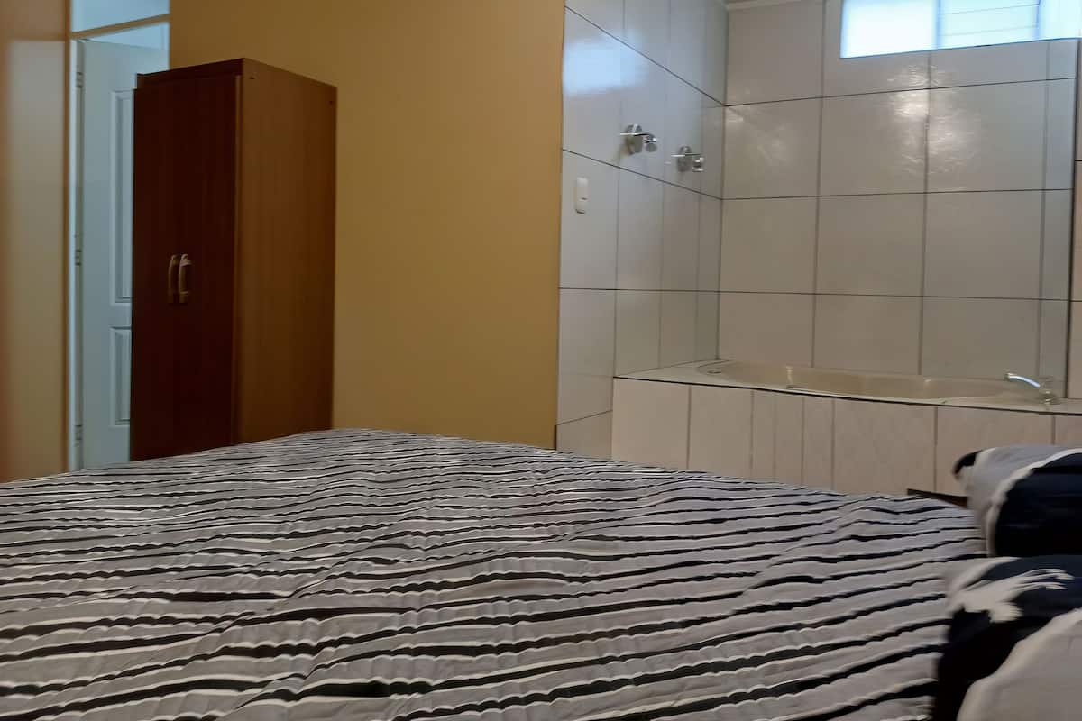 Ein Schlafzimmer mit Bett, Kleiderschrank und einem Badezimmer mit Badewanne.