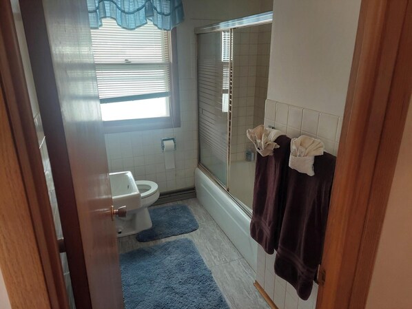 A small bathroom with a toilet, a shower, and a window with blinds. - Beautiful Cozy home in Philipsburg (Philipsburg)