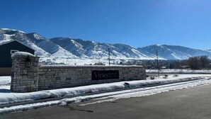 A stone building with a sign reading "Vineyard" in front of snow-covered mountains under a clear blue sky.
