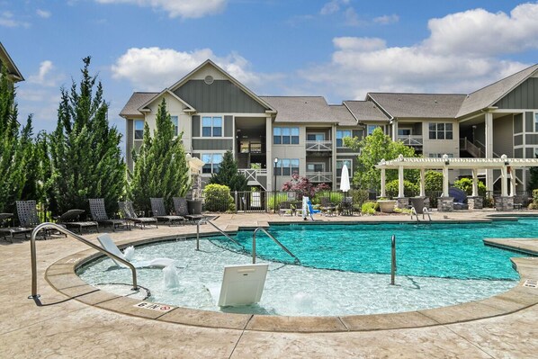 A swimming pool with a lifeguard chair, lounge chairs, and a covered seating area.