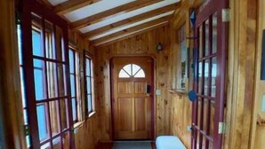 A wooden hallway with a bench, a door with a window, and a small rug on the floor. - Cozy Hillside Hideaway on Lake Canadarago (Richfield Springs)