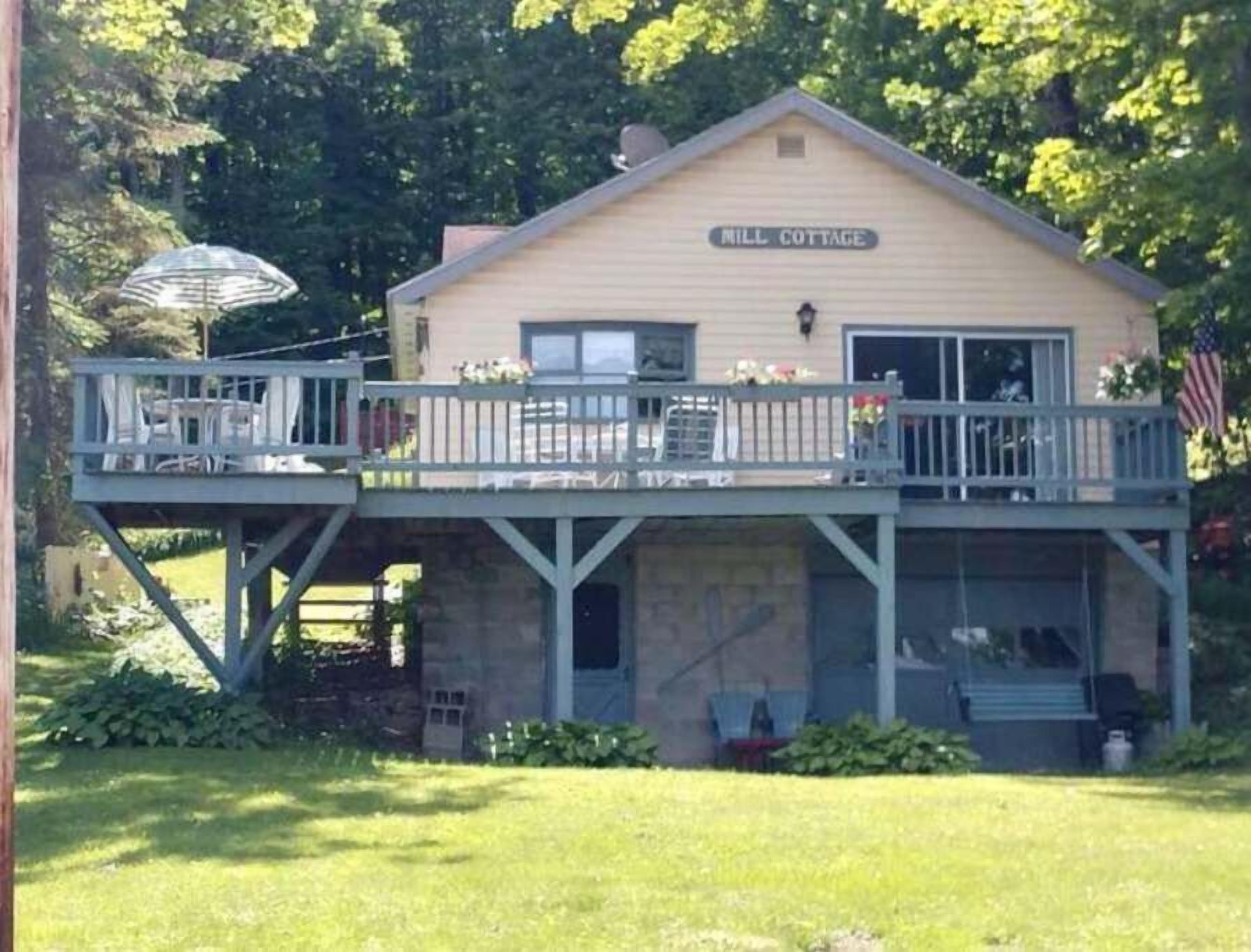 A two-story building labeled "Mill Cottage" with a balcony and outdoor seating area.