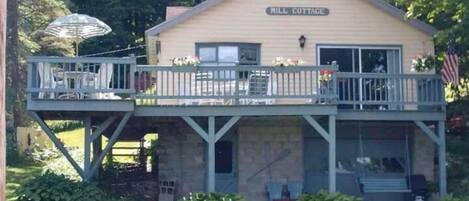 A two-story building labeled "Mill Cottage" with a balcony and outdoor seating area.