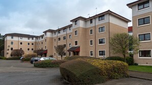 A multi-story residential building with a parking area and well-maintained landscaping. - A modern 2-bedroom apartment in a quiet neighbourhood . Sleeps 4 (Edinburgh)
