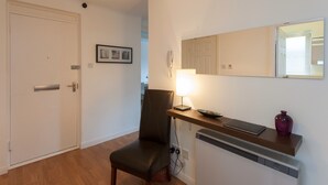 A room with a door, a chair, a table with a lamp, a mirror, and a radiator. - A modern 2-bedroom apartment in a quiet neighbourhood . Sleeps 4 (Edinburgh)