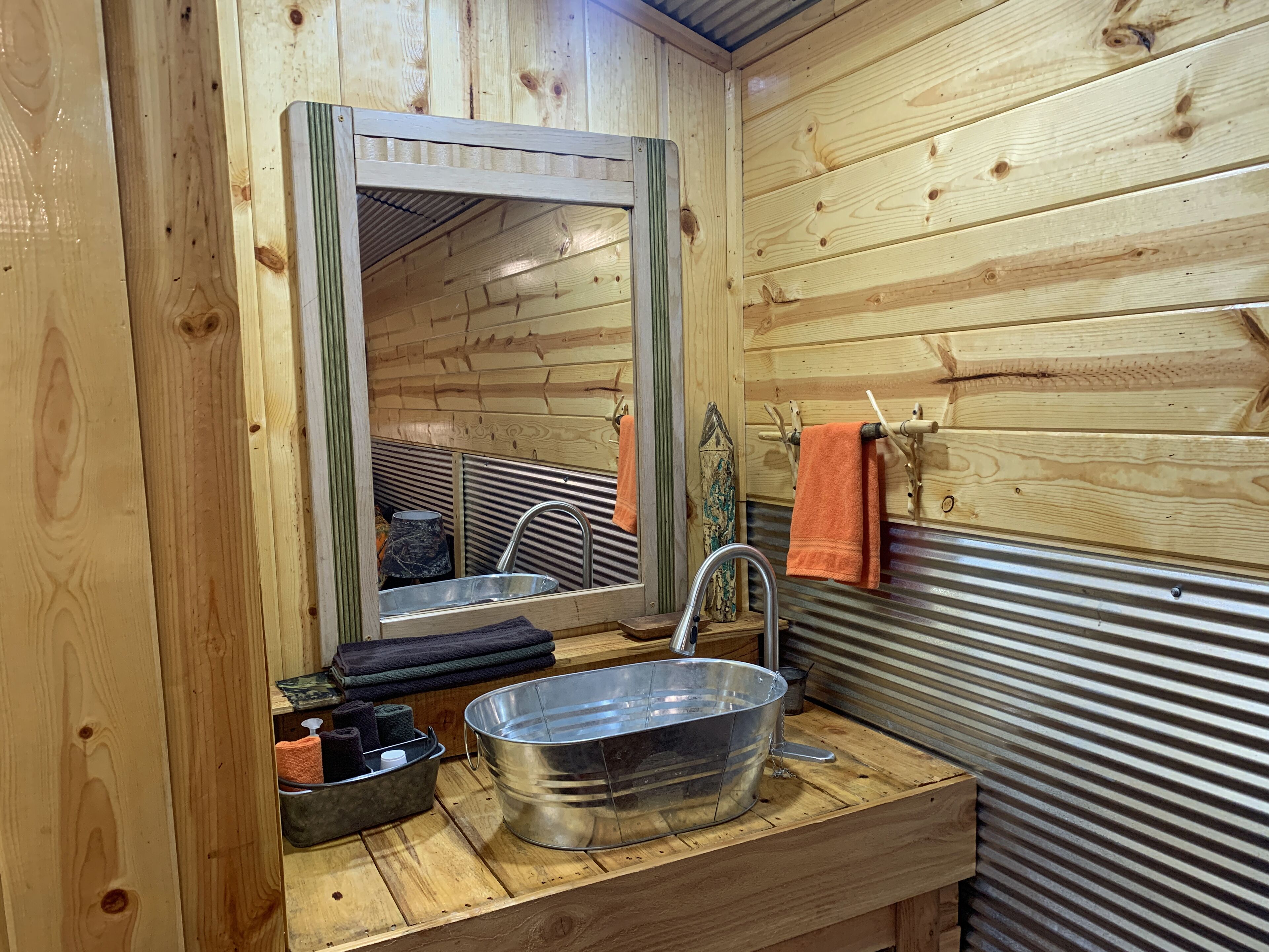 A wooden cabin bathroom with a sink, mirror, and towel rack.