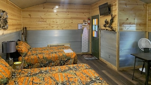 Une cabane confortable avec deux lits, une petite table, une chaise et un ventilateur.
